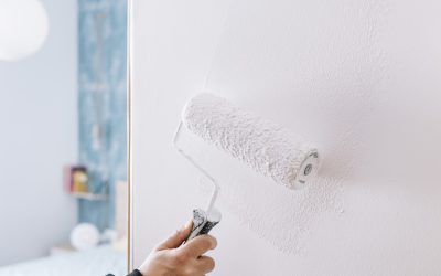 hand painting a wall in white with a roller, home decoration and renovation concept, horizontal photo with copy space for text